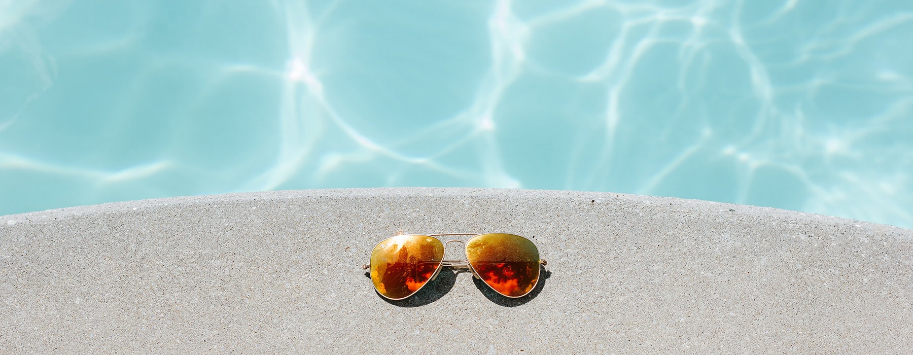 Sunglasses sitting on the ledge of the pool 